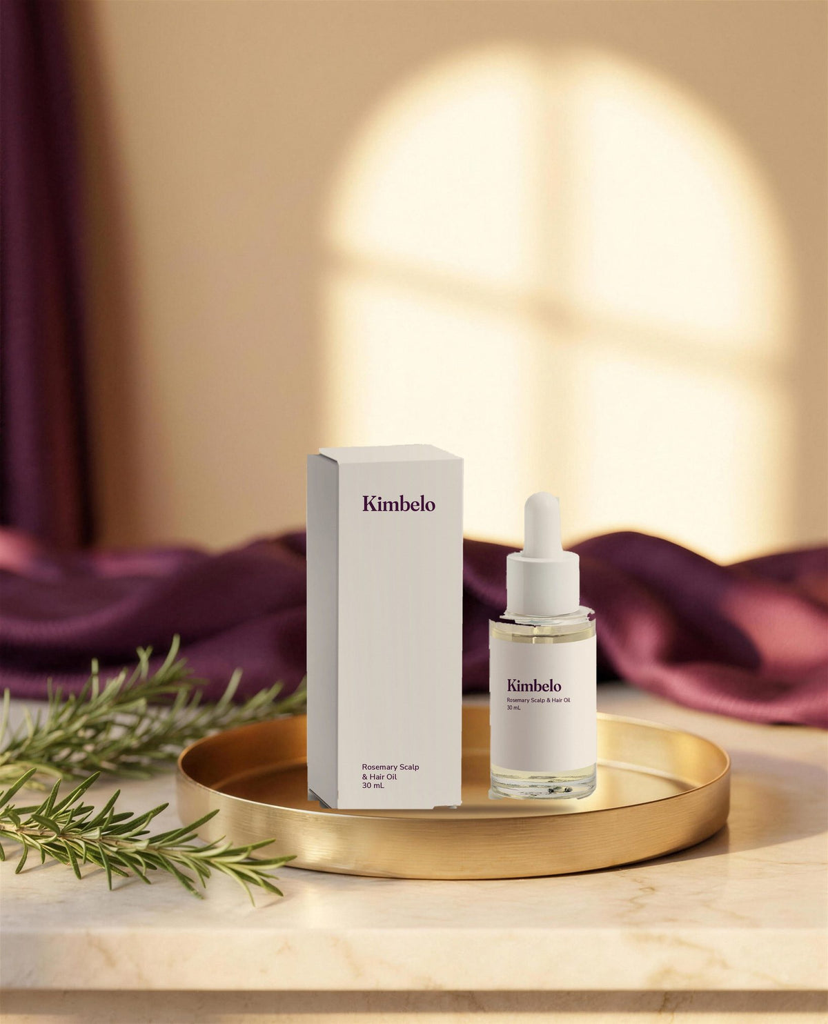 Kimbelo Rosemary Scalp & Hair Oil dropper bottle and carton on a gold tray with fresh rosemary sprigs and a plum cloth